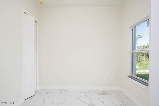 unfurnished room with marble finish floor and baseboards