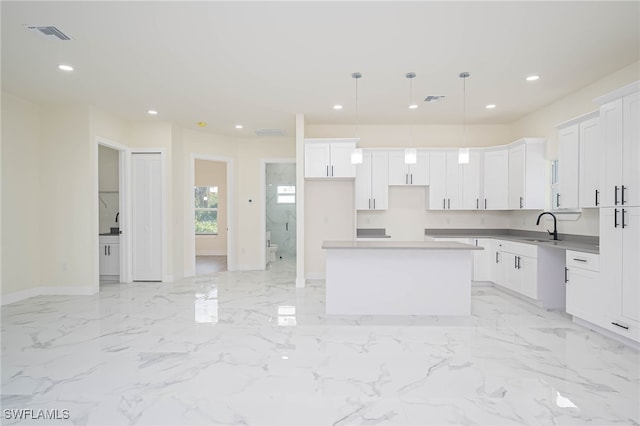 kitchen with a sink, marble finish floor, a kitchen island, and recessed lighting