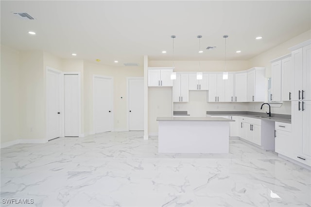 kitchen featuring recessed lighting, white cabinetry, a kitchen island, and a sink