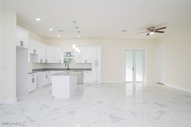 kitchen featuring recessed lighting, a kitchen island, white cabinets, open floor plan, and marble finish floor