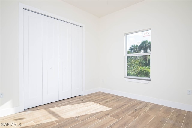 unfurnished bedroom with wood tiled floor, baseboards, and a closet