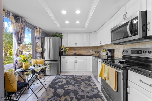 kitchen featuring stainless steel appliances, light tile patterned floors, a raised ceiling, backsplash, and white cabinets