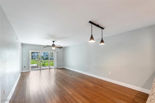 unfurnished room with ceiling fan, baseboards, and dark wood finished floors