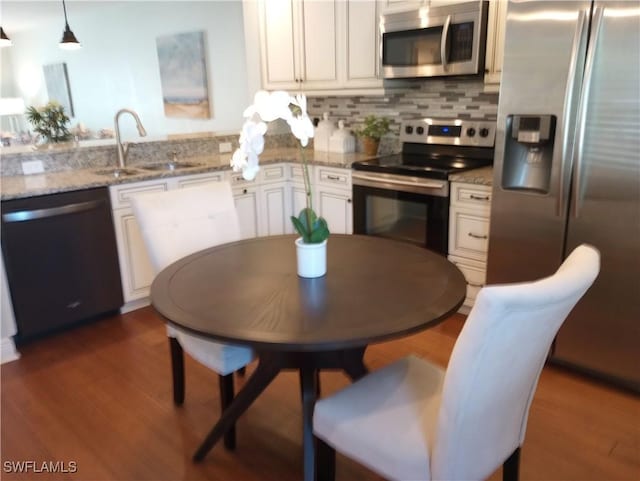 kitchen featuring decorative backsplash, appliances with stainless steel finishes, dark wood finished floors, and a sink