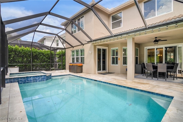 view of pool featuring an in ground hot tub, glass enclosure, a patio area, and ceiling fan