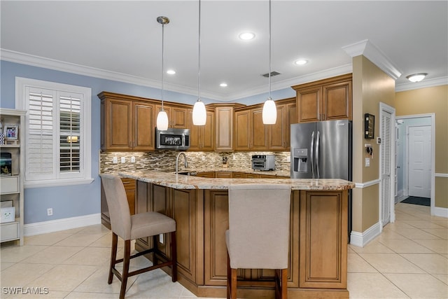 kitchen with hanging light fixtures, ornamental molding, stainless steel appliances, a breakfast bar area, and light stone countertops