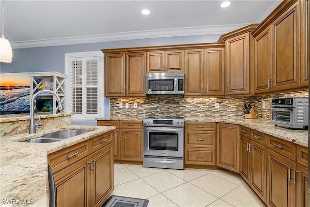 kitchen with pendant lighting, sink, stainless steel appliances, light stone countertops, and ornamental molding