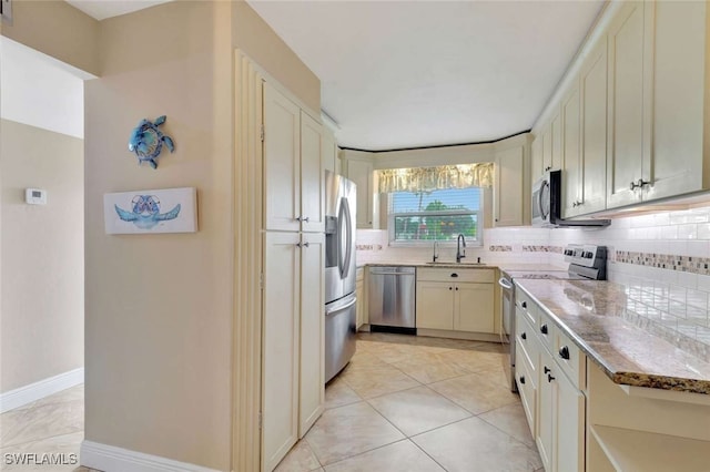 kitchen featuring appliances with stainless steel finishes, backsplash, sink, and light tile patterned floors