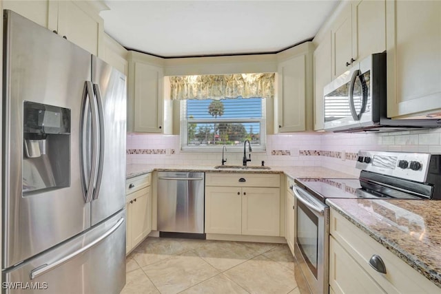 kitchen with appliances with stainless steel finishes, cream cabinetry, and plenty of natural light