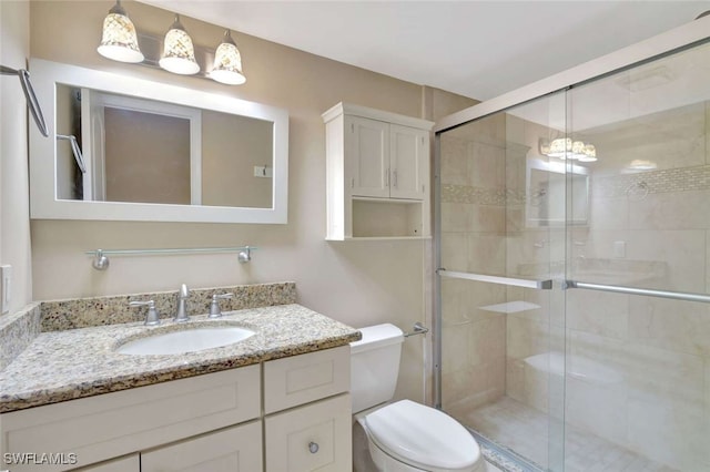 bathroom with vanity, toilet, and a shower with shower door