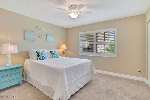 bedroom featuring light carpet, ceiling fan, and a textured ceiling