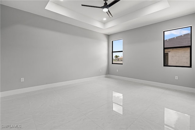 unfurnished room featuring ceiling fan and a raised ceiling