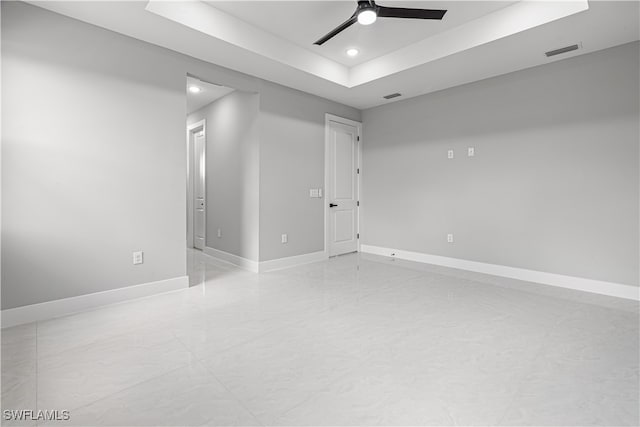 unfurnished room with ceiling fan and a tray ceiling