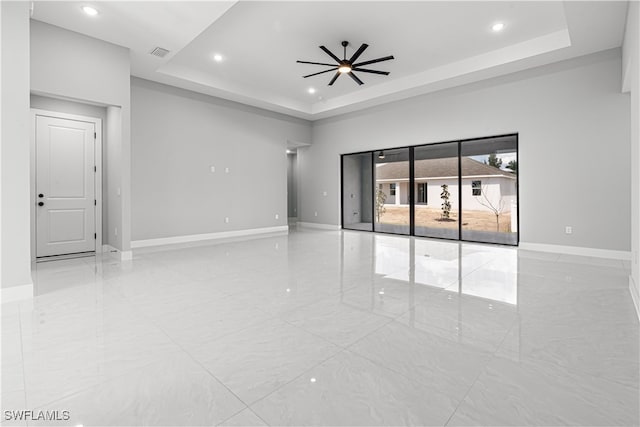 unfurnished room featuring ceiling fan and a raised ceiling