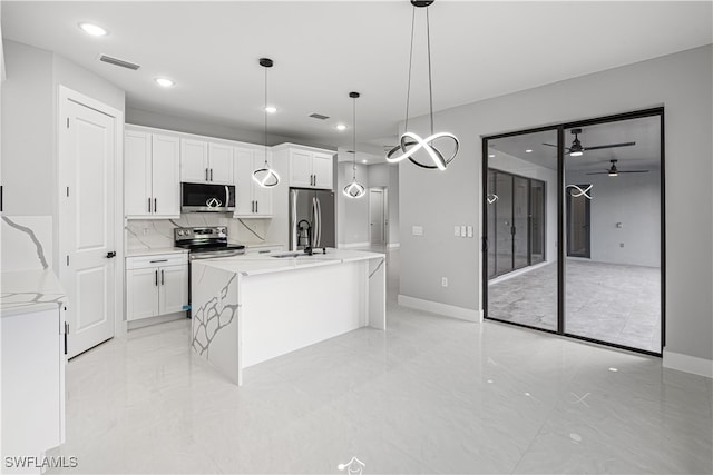 kitchen featuring appliances with stainless steel finishes, an island with sink, white cabinetry, and pendant lighting