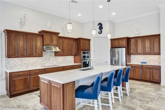 kitchen featuring a center island with sink, a kitchen breakfast bar, pendant lighting, a towering ceiling, and stainless steel appliances