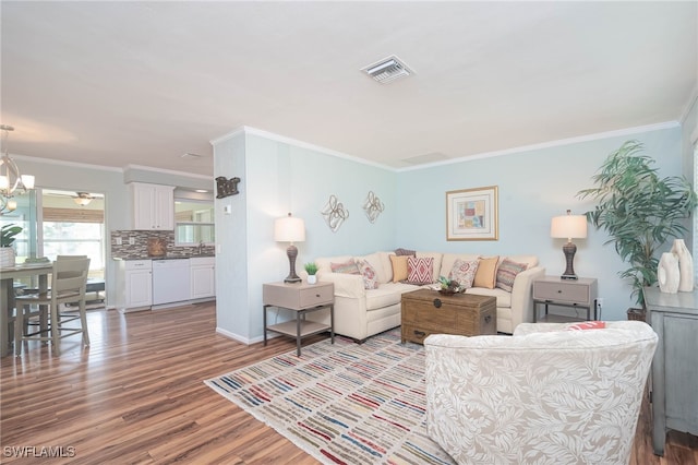 5807 Cubles Dr, Bokeelia, FL 33922 - living area with visible vents, wood finished floors, baseboards, an inviting chandelier, and ornamental molding