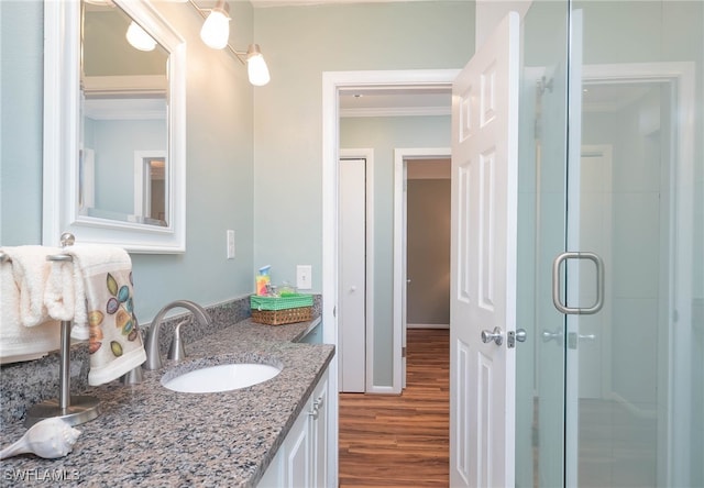 bathroom with vanity, ornamental molding, a shower with door, and hardwood / wood-style floors