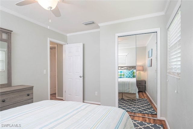 bedroom with a closet, ceiling fan, hardwood / wood-style flooring, and crown molding