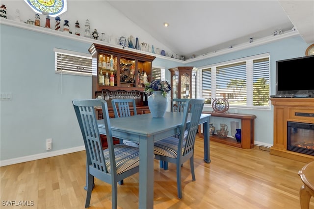 dining room with light wood-type flooring and high vaulted ceiling