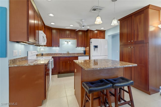 kitchen with ceiling fan, a center island, pendant lighting, white appliances, and a breakfast bar