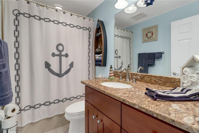 bathroom featuring tile patterned floors, vanity, toilet, and walk in shower