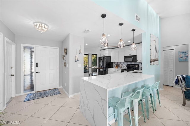 kitchen with backsplash, black appliances, kitchen peninsula, a kitchen breakfast bar, and white cabinets