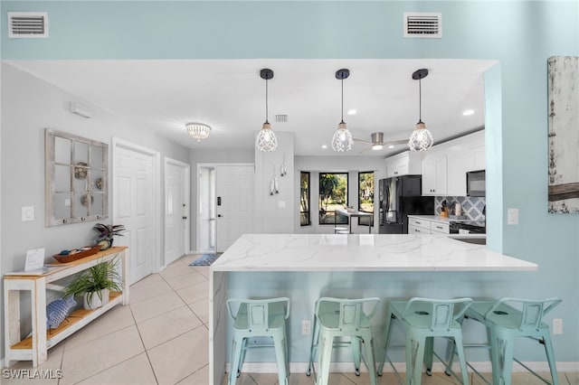 kitchen featuring white cabinetry, kitchen peninsula, backsplash, hanging light fixtures, and black appliances