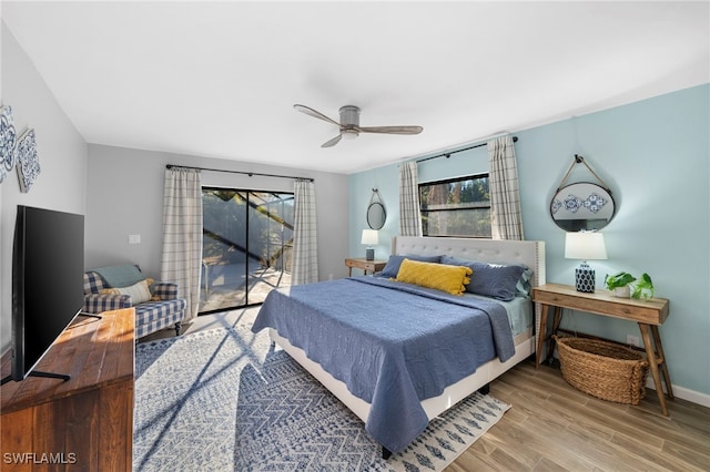 bedroom with baseboards, access to exterior, wood finished floors, and multiple windows
