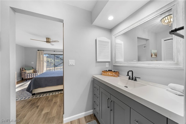 bathroom featuring visible vents, vanity, wood finished floors, baseboards, and ceiling fan