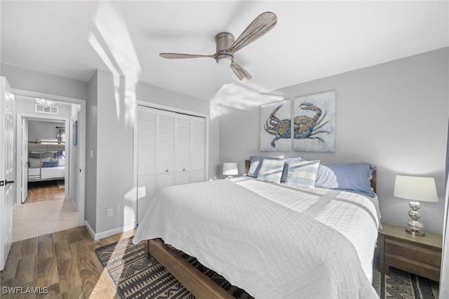 bedroom with a closet, visible vents, wood finished floors, baseboards, and ceiling fan