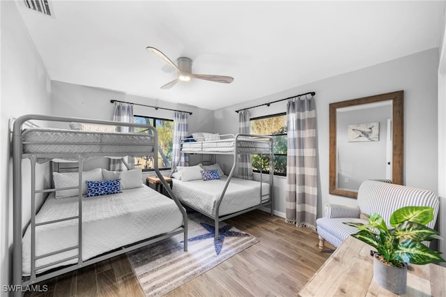 bedroom with baseboards, ceiling fan, wood finished floors, and visible vents