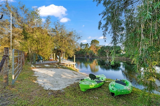 view of home's community featuring fence, a water view, and a dock