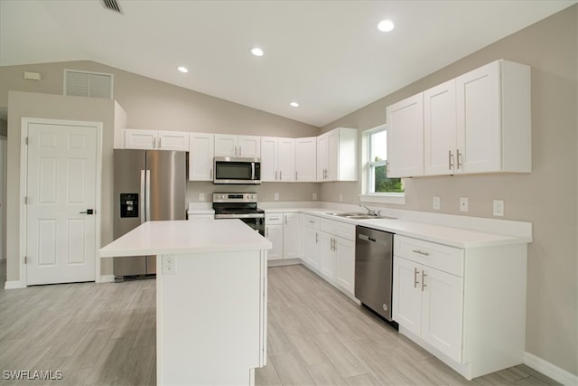 kitchen with white cabinets, stainless steel appliances, lofted ceiling, a center island, and sink