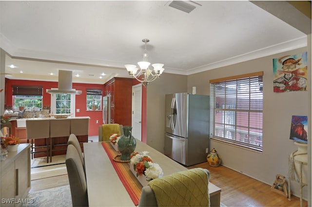 dining room featuring light hardwood / wood-style floors, ornamental molding, and a chandelier