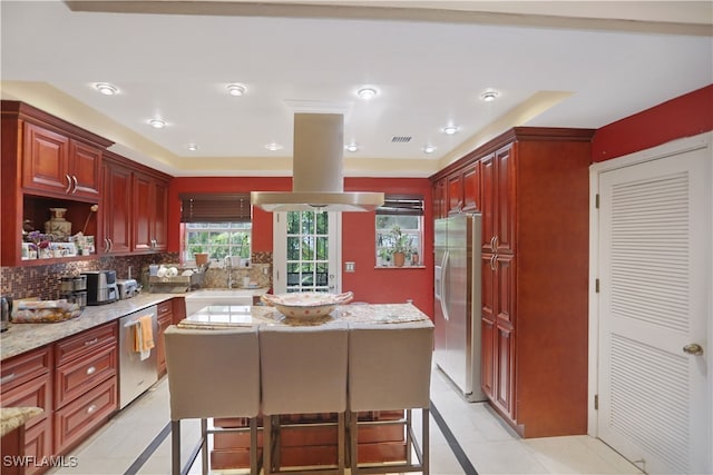 kitchen with tasteful backsplash, stainless steel appliances, light stone countertops, and a kitchen bar