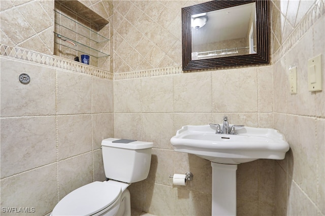 bathroom featuring toilet, tile walls, and sink