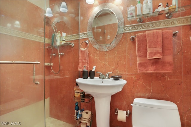 bathroom featuring toilet, tile walls, and a shower with shower door