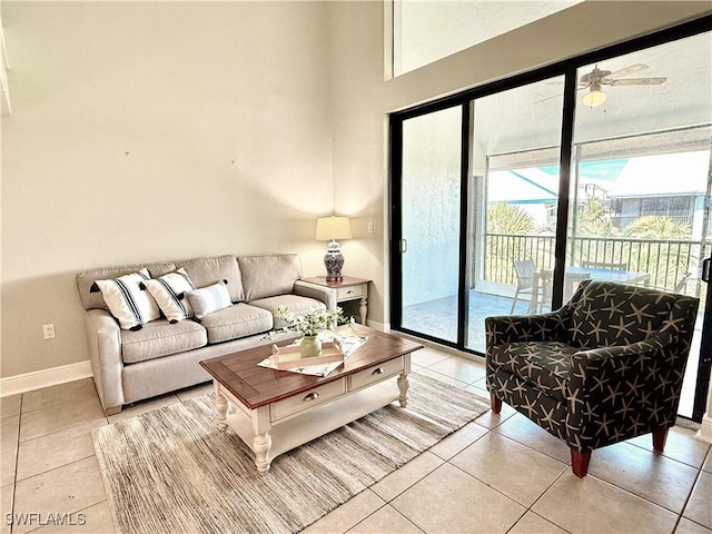 living room with a high ceiling, ceiling fan, baseboards, and light tile patterned floors