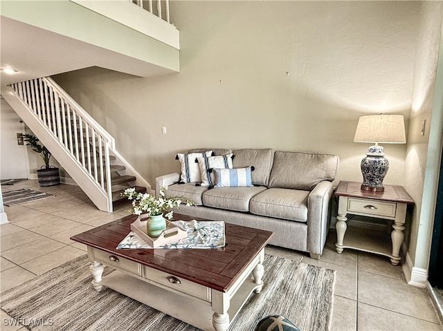 living room with light tile patterned floors, stairs, and baseboards