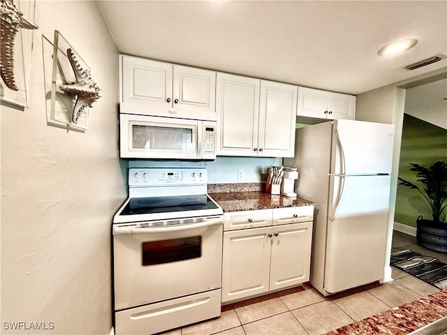 kitchen with white appliances, white cabinets, visible vents, and light tile patterned floors