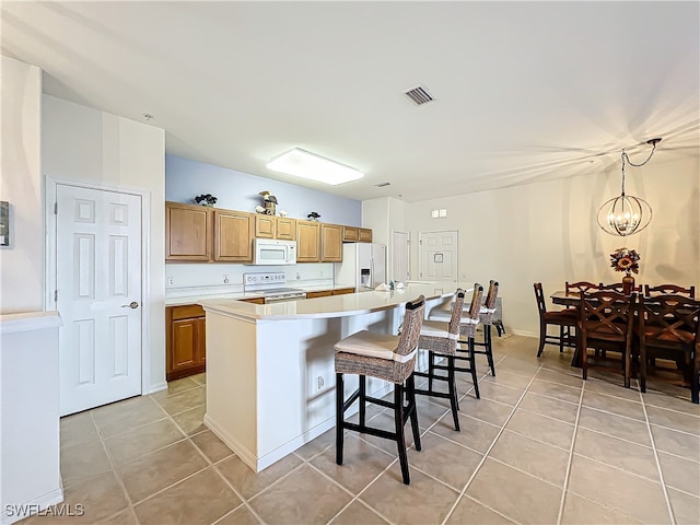 kitchen with white appliances, a center island, pendant lighting, a notable chandelier, and light tile patterned floors