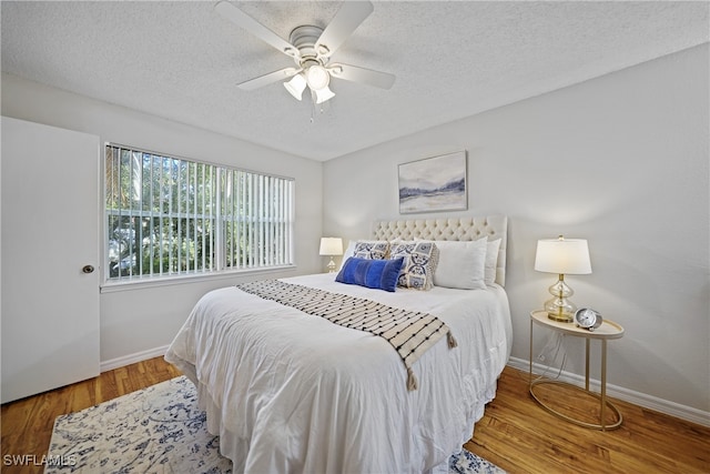 bedroom with ceiling fan, a textured ceiling, and hardwood / wood-style floors