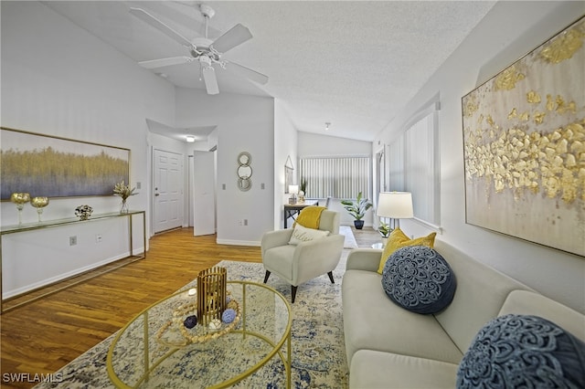 living room with ceiling fan, a textured ceiling, hardwood / wood-style floors, and vaulted ceiling