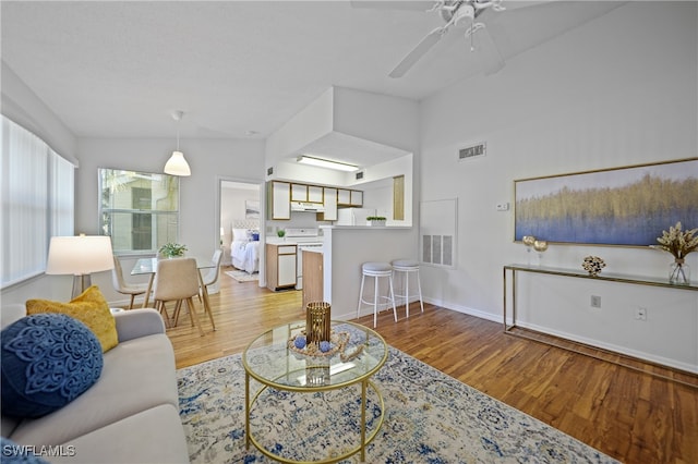 living room with ceiling fan, vaulted ceiling, and hardwood / wood-style floors