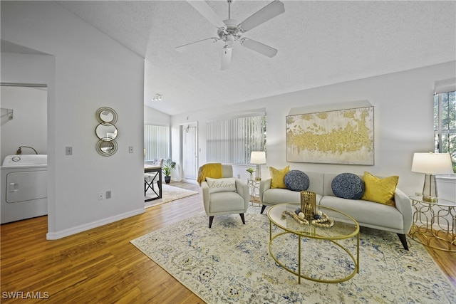 living room with ceiling fan, hardwood / wood-style floors, vaulted ceiling, washer / clothes dryer, and a textured ceiling