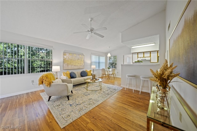 living room featuring ceiling fan, vaulted ceiling, light hardwood / wood-style floors, and a textured ceiling