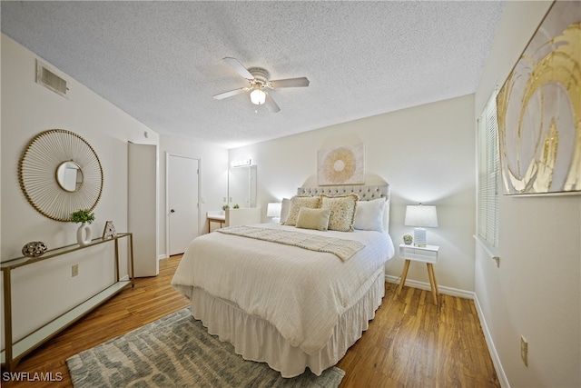 bedroom featuring ceiling fan, a textured ceiling, connected bathroom, and wood-type flooring