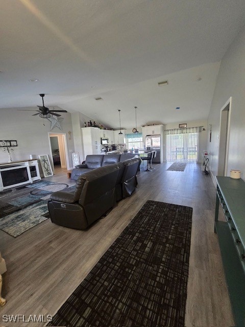 living room featuring vaulted ceiling, dark hardwood / wood-style flooring, and ceiling fan