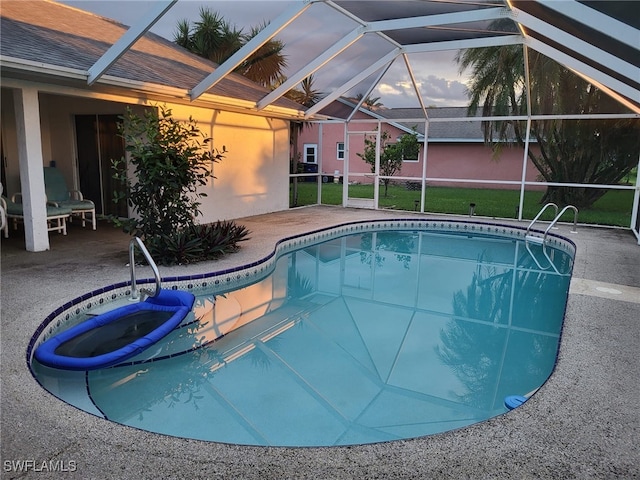 pool at dusk featuring a lanai, a patio area, and a jacuzzi